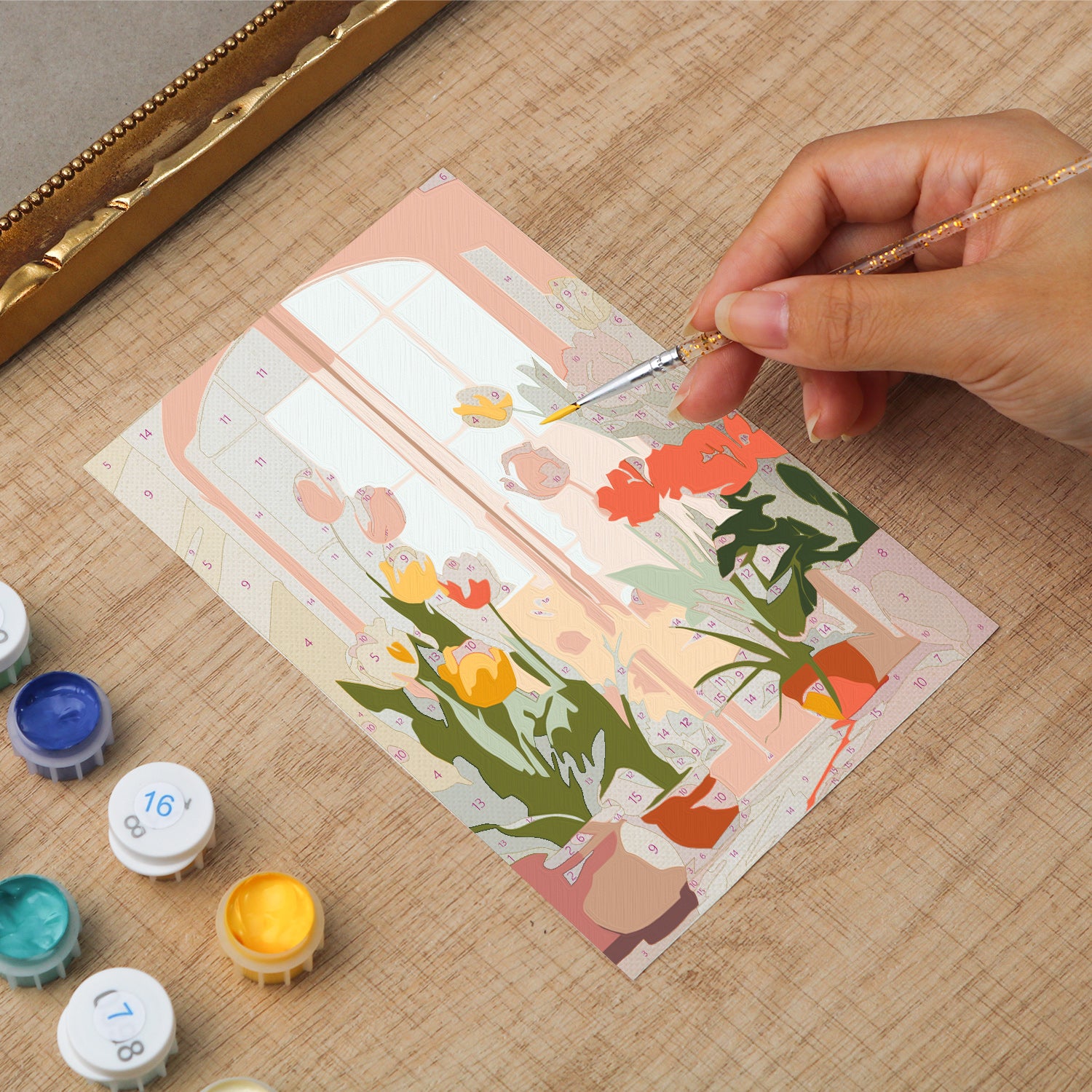 Framed mini paint by numbers of a cozy window filled with blooming flowers and warm decorative details